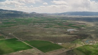 AX130_231E - 5.5K aerial stock footage of approaching small rural town, farmland, distant mountains, Loa, Utah