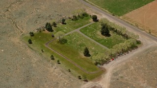 AX130_239 - 5.5K aerial stock footage of orbiting a tiny cemetery by rural road, dirt fields, Bicknell, Utah