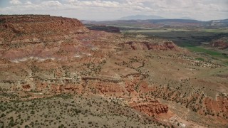 AX130_240E - 5.5K aerial stock footage of approaching a mesa, surrounded by farmland, Capitol Reef National Park, Utah