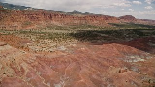 AX130_243 - 5.5K aerial stock footage of approaching a mesa overlooking valley desert vegetation, Capitol Reef National Park, Utah