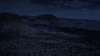 AX130_245_DFN - Aerial stock footage of 4K day for night color corrected aerial footage of flying by mesas, pan and approach a butte, Capitol Reef National Park, Utah