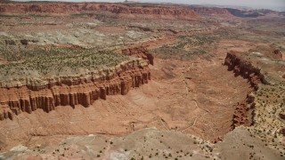 AX130_250E - 5.5K aerial stock footage of flying over dry riverbed through canyon between mesas, Capitol Reef National Park, Utah