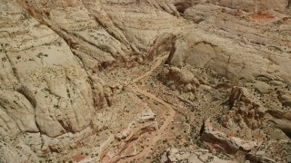 AX130_276E - 5.5K aerial stock footage fly over dirt road, tilt to reveal Waterpocket Fold rock formations, Capitol Reef National Park, Utah
