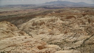 AX130_287 - 5.5K aerial stock footage of flying over the Waterpocket Fold rock formations, approaching mesas, Capitol Reef National Park, Utah