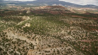 AX130_337E - 5.5K aerial stock footage of flying over desert hills covered in vegetation, approach a peak, Capitol Reef National Park, Utah