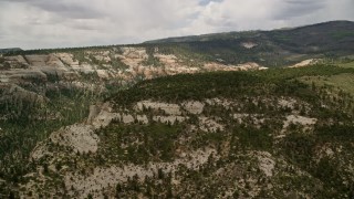 AX130_351E - 5.5K aerial stock footage of an approach to a wide canyon with desert vegetation, Dixie National Forest, Utah