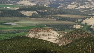 AX130_369E - 5.5K aerial stock footage of flying by rural homes, fields, pond, and flat-topped mountain, Boulder, Utah