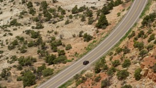 AX130_376E - 5.5K aerial stock footage of a black SUV on Route 12, Boulder, Utah