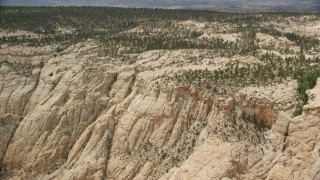 AX130_386E - 5.5K aerial stock footage an approach to top of a canyon, desert vegetation, trees, Grand Staircase-Escalante National Monument, Utah