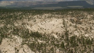 AX130_388E - 5.5K aerial stock footage of flying over mountain ridge, revealing desert road, Grand Staircase-Escalante National Monument, Utah