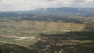AX130_394E - 5.5K aerial stock footage of flying over a valley, approaching a mountain ridge, Grand Staircase-Escalante National Monument, Utah