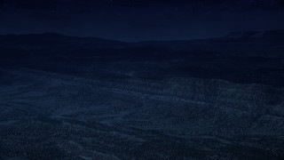 AX130_396_DFN - Aerial stock footage of 4K day for night color corrected aerial footage of approaching a mountain ridge from over a wide valley, Grand Staircase-Escalante National Monument, Utah