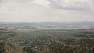 AX130_419 - 5.5K aerial stock footage of flying by green valley beyond mountain ridges, Grand Staircase-Escalante National Monument, Utah