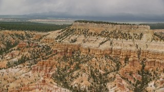 AX130_430E - 5.5K aerial stock footage of passing by groups of hoodoos around base of mesa, Bryce Canyon National Park, Utah