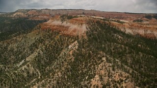 AX130_451E - 5.5K aerial stock footage of flying by small mesa with hoodoos, trees, desert vegetation at Bryce Canyon National Park, Utah