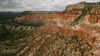 AX130_461E - 5.5K aerial stock footage of flying by hoodoos on a steep mesa cliff and across a canyon, Bryce Canyon National Park, Utah