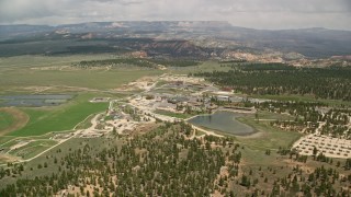 AX130_494E - 5.5K aerial stock footage orbit small town and hotels near fields, a pond and forest, Bryce, Utah