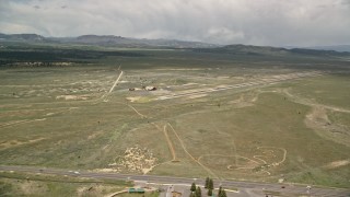 AX130_496E - 5.5K aerial stock footage of orbiting single runway, wood hangar, Bryce Canyon Airport, Utah