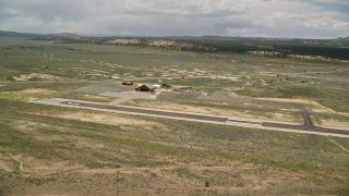AX130_498E - 5.5K aerial stock footage of approaching single prop plane, helicopters, near wooden hangar, Bryce Canyon Airport, Utah