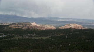 AX131_006 - 5.5K aerial stock footage of flying by green forest, mesas in the background, Bryce Canyon National Park, Utah