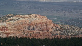 AX131_007 - 5.5K aerial stock footage of flying by cliffside hoodoos, buttes, distant valley, Bryce Canyon National Park, Utah
