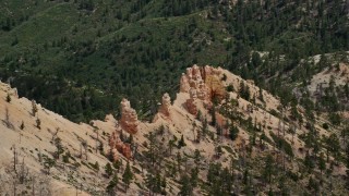 AX131_017 - 5.5K aerial stock footage of flying by hoodoos, revealing forested valley, Bryce Canyon National Park, Utah