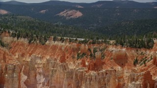 AX131_024 - 5.5K aerial stock footage of flying by Pink Cliffs, hoodoos, topped with trees, Bryce Canyon National Park, Utah