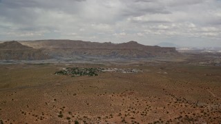 AX131_116E - 5.5K aerial stock footage of flying by a small desert town, Big Water, Utah