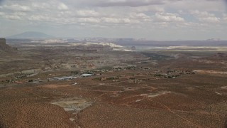 AX131_118E - 5.5K aerial stock footage of a tiny desert town, mesa in the distance, Big Water, Utah