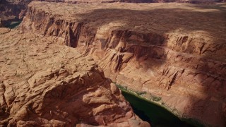 AX131_201E - 5.5K aerial stock footage of flying over Colorado River at the bottom of deep Glen Canyon, Arizona