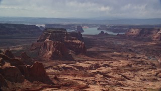 AX132_011E - 5.5K aerial stock footage of flying by buttes, Lake Powell in the background, Navajo Nation Reservation, Arizona