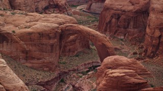 AX132_045E - 5.5K aerial stock footage of passing a natural stone arch, Rainbow Bridge National Monument, Utah