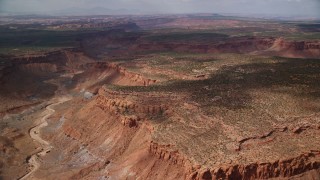 AX132_083E - 5.5K aerial stock footage of passing by dry riverbed in desert canyon, Navajo Nation Reservation, Arizona, Utah