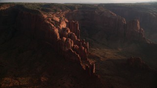 AX133_055 - 5.5K stock footage aerial video of passing by rock formations, Hunt's Mesa, Monument Valley, Utah, Arizona, sunset