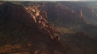 AX133_055E - 5.5K aerial stock footage of passing Hunt's Mesa and rock formations, Monument Valley, Utah, Arizona, sunset