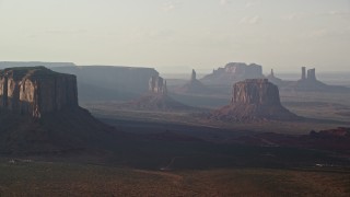 AX133_065E - 5.5K aerial stock footage of flying by buttes in a wide desert valley, Monument Valley, Utah, Arizona, twilight