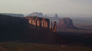 AX133_068 - 5.5K aerial stock footage of passing buttes in a desert valley, Monument Valley, Utah, Arizona, twilight