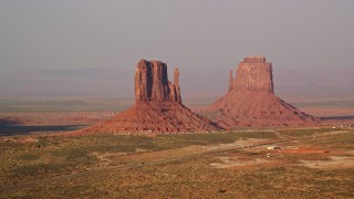 AX133_082E - 5.5K aerial stock footage of passing by West and East Mitten Buttes, Monument Valley, Utah, Arizona, twilight