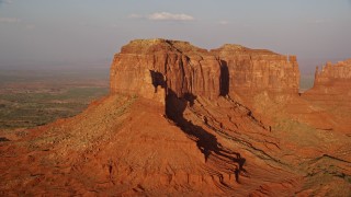 AX133_093E - 5.5K aerial stock footage flying by side of Brighams Tomb Butte, Monument Valley, Utah, Arizona, sunset