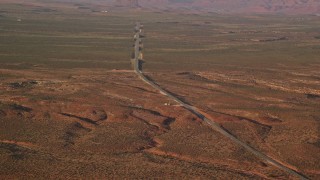 AX133_097E - 5.5K aerial stock footage of Highway 163 through desert valley, Monument Valley, Utah, Arizona, twilight