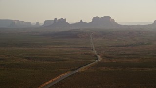 AX133_103E - 5.5K aerial stock footage flyby highway leading to buttes, Monument Valley, Utah, Arizona, twilight