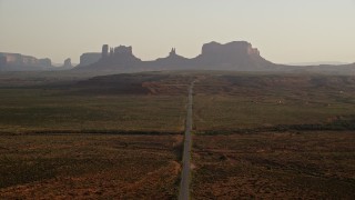 AX133_107E - 5.5K aerial stock footage fly over highway and approach buttes, Monument Valley, Utah, Arizona, twilight