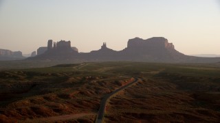 AX133_113 - 5.5K stock footage aerial video pass by highway leading to buttes, Monument Valley, Utah, Arizona, twilight