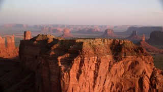 AX133_129 - 5.5K stock footage aerial video of fly over butte, revealing more buttes in Monument Valley, Utah, Arizona, twilight