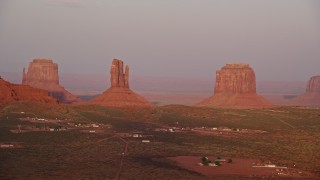 AX133_164E - 5.5K aerial stock footage of flying past buttes in a desert valley, Monument Valley, Utah, Arizona, sunset