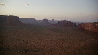 AX133_188 - 5.5K aerial stock footage of approaching Merrick Butte and Elephant Butte, Monument Valley, Utah, Arizona, sunset