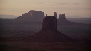 AX133_196 - 5.5K aerial stock footage of East Mitten Butte in a hazy valley, Monument Valley, Utah, Arizona, sunset