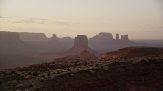 AX133_204E - 5.5K aerial stock footage of passing by distant buttes through thick haze, Monument Valley, Utah, Arizona, twilight