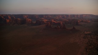 AX133_207E - 5.5K aerial stock footage of passing by buttes, rock formations and mesa in Monument Valley, Utah, Arizona, twilight
