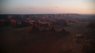 AX133_208 - 5.5K stock footage aerial video of passing by buttes, rock formations and mesa in Monument Valley, Utah, Arizona, twilight